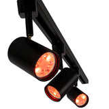 Zwarte LED railspot met rode verlichting, gemonteerd op een 3-fase railsysteem, schuin van onderen gefotografeerd.
