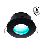 Waterdichte zwarte LED inbouwspot met RGB-verlichting, frontaal schuin van onderen gefotografeerd, met helder blauw licht en metalen bevestigingsklemmen zichtbaar.