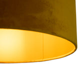 Detailaanzicht van een ronde, moderne lampenkap in okergeel fluweel met warme lichtgloed aan de binnenzijde, geschikt voor hanglampen of staande lampen.