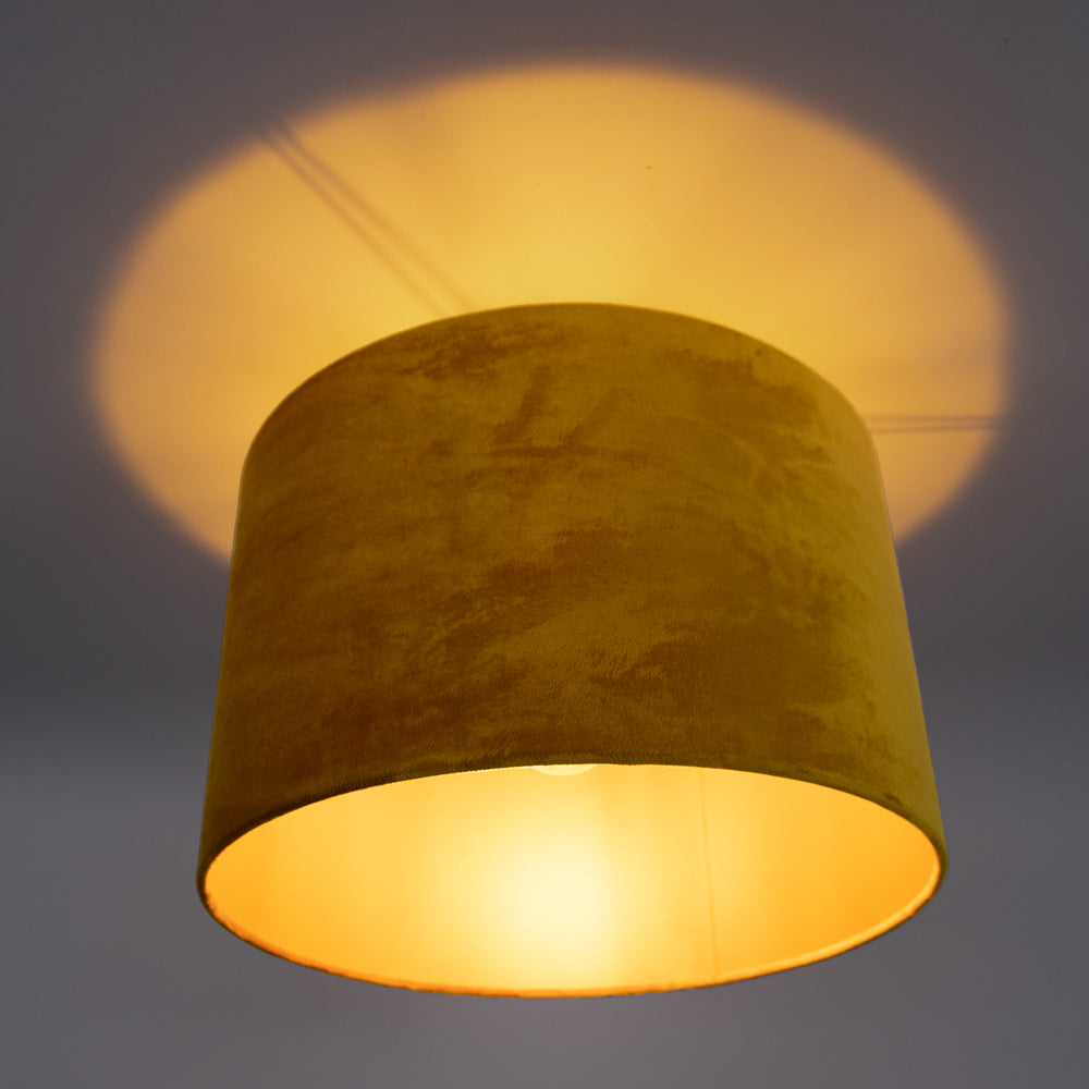 Gele velvet plafondlamp met warme lichtuitstraling, gezien van schuin-onderaanzicht tegen een neutrale achtergrond.