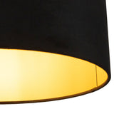 Zijaanzicht van een zwarte plafondlampenkap met goudkleurige binnenzijde die warm licht uitstraalt.