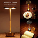 Oplaadbare en draadloze tafellamp in modern design, weergegeven in meerdere aanzichten: close-up vooraanzicht van de lamp op een houten tafel, sfeervolle setting bovenaanzicht naast een dinerbord met wijn, en bovenaanzicht naast een open boek en glas whisky — ideaal voor multifunctioneel gebruik zoals lezen of dineren.