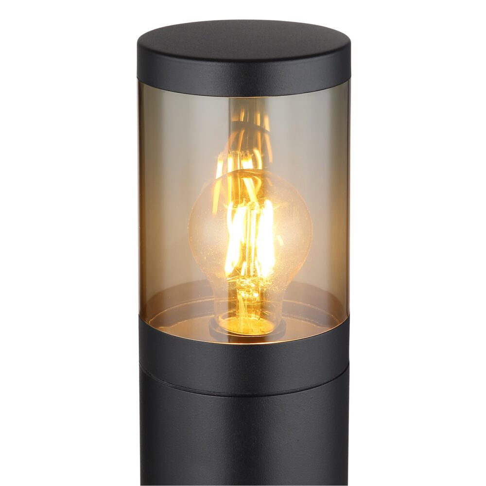 Close-up vooraanzicht van een moderne zwarte buitenlamp met cilindervormig design, transparant glas en zichtbare gloeilamp met warm licht, ideaal voor tuinverlichting of opritverlichting.