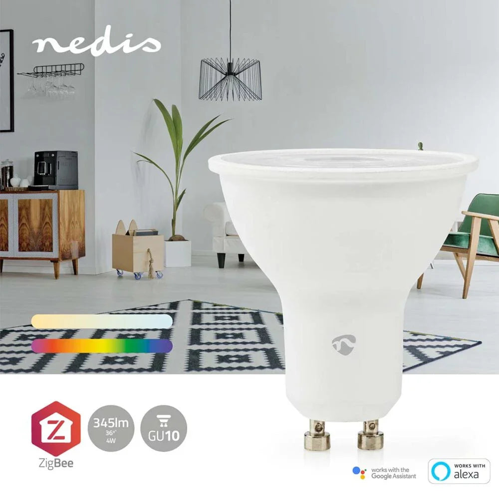 Nedis slimme GU10 LED-lamp met ZigBee-technologie, 345 lumen, 4W, in een modern interieur van een woonkamer met zicht op een houten kast, koffiemachine, fauteuil en groene stoel – vooraanzicht van de lamp met ondersteuning voor Google Assistant en Alexa.