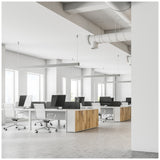 Modern open kantoorinterieur met meerdere bureaus, ergonomische bureaustoelen en grote computerschermen, gezien vanuit een schuin zijaanzicht. Heldere ruimte met veel daglicht dankzij grote ramen en minimalistische inrichting met houten accenten.